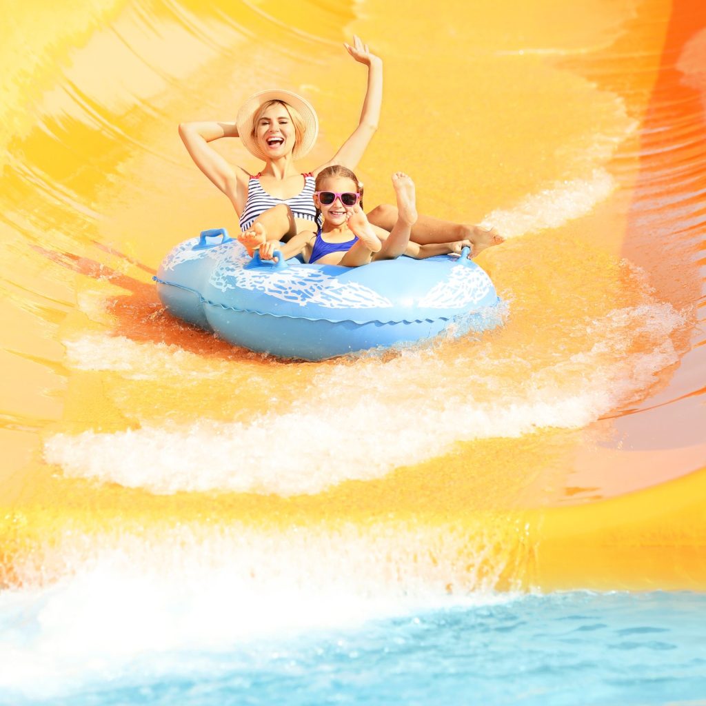 Little girl and her mother having fun in aqua park